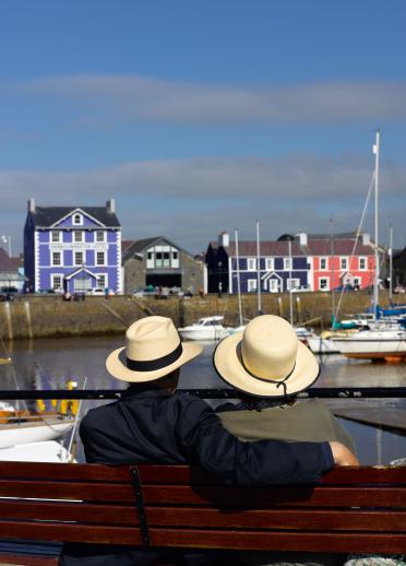 Ein Paar blickt auf den Hafen von Aberaeron und das Harbourmaster Hotel im Hintergrund.