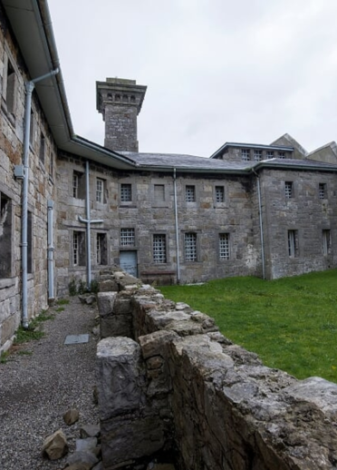 The courtyard within a stone gaol - a grassy arare overlooked by cells.