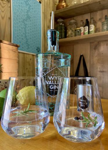 A bottle of Wye Valley Gin made at Silver Circle Distillery and two glasses with gin, rosemary and blueberries in them.