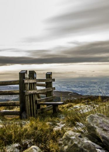 A walking stile of the top of a mountain with dramatic views and sky.