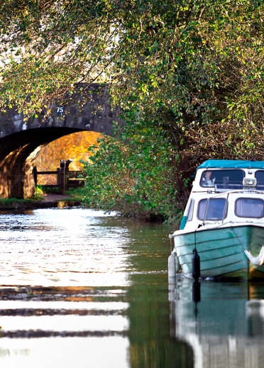 A boat on a canal with a bridge in the background.