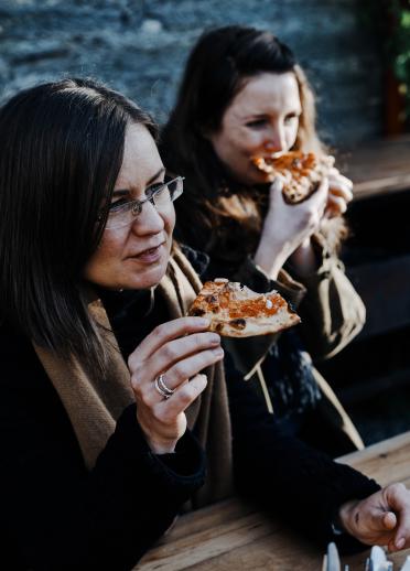 two women eating pizza.