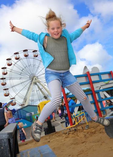 girl jumping in air in fairground.