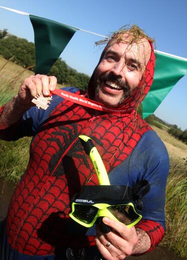 man in spiderman outfit holding snorkel and medal.