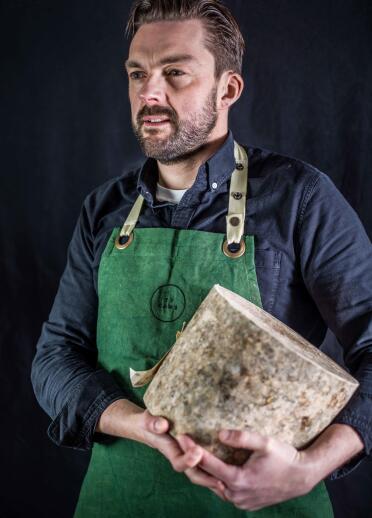 Ein Mann hält einen riesigen Laib Käse