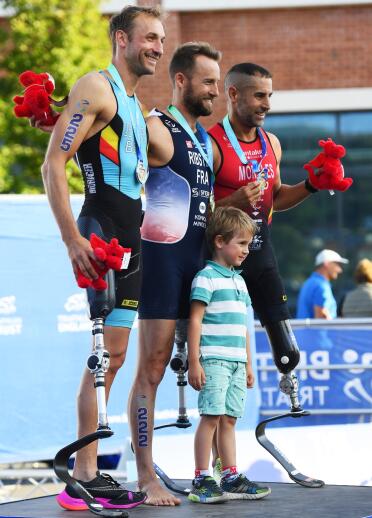 Three men and a small boy with medals on a podium.