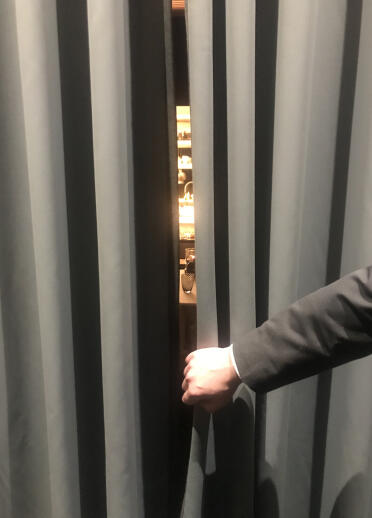 A hand opening a black curtain to reveal a restaurant interior.