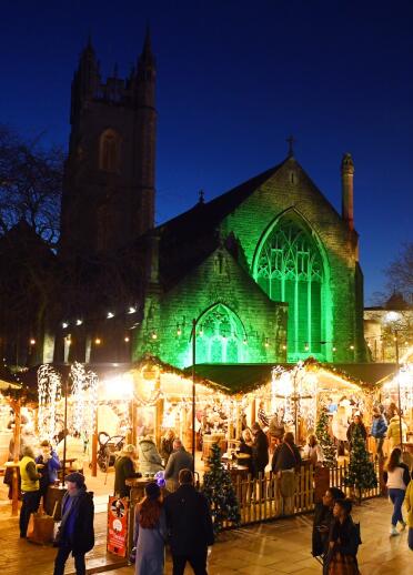 Christmas market stalls at night and church in background.
