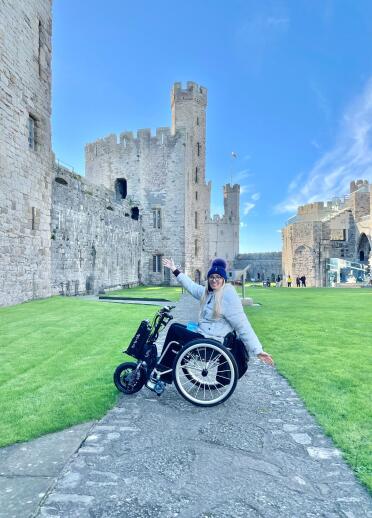 A woman in a wheelchair in castle grounds.