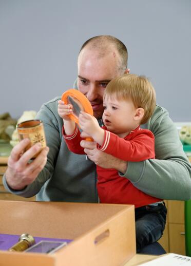A man and a young child handling objects from a box.