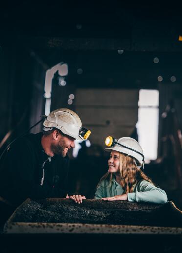 A man in a miner's helmet talking to a young person, also wearing a miner's helmet.