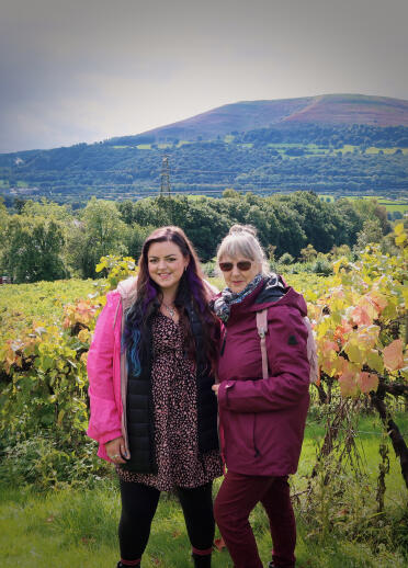 Two women with the backdrop of a vineyard