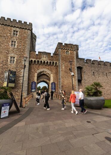 Entrance to a castle with people walking through a gatehouse.