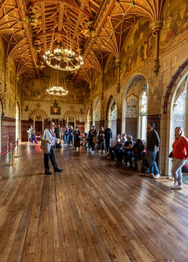 A man giving a tour to a group of people inside an ornate castle room. 