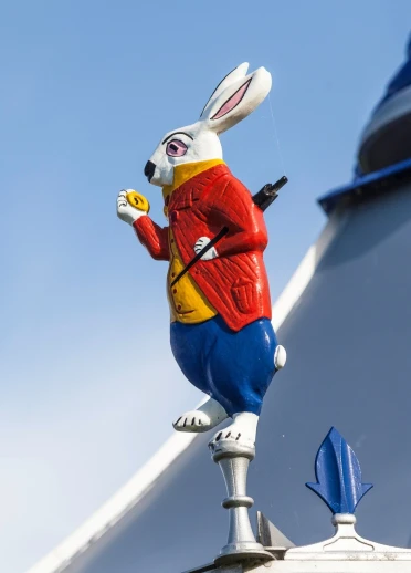 Painted white rabbit sculpture on a building roof.