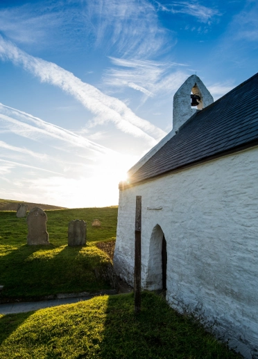 Eine kleine, weiß getünchte Kapelle im Sonnenlicht.