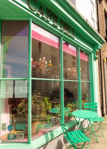 Exterior of a cafe with a large window front and seating outside.