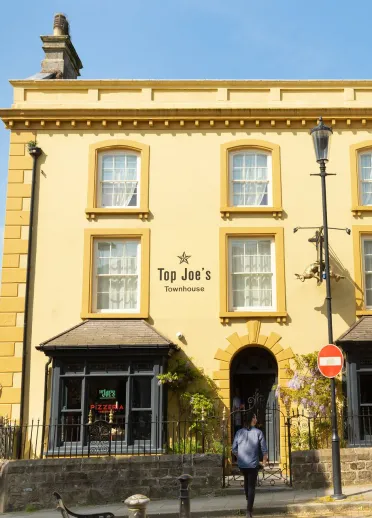A yellow painted shop with bay windows. 
