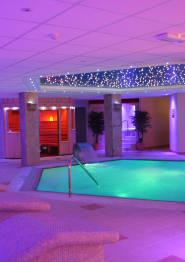 fluorescently lit spa pool with loungers.
