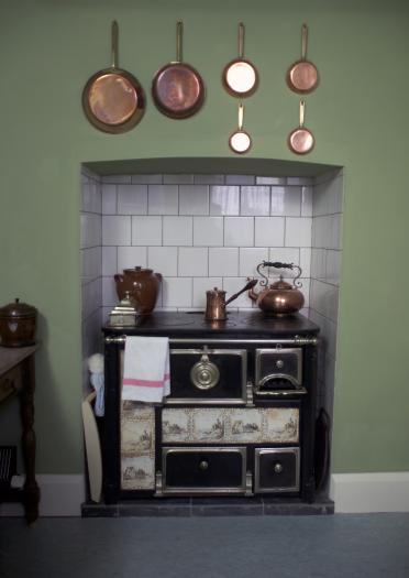 An aga and copper pots, pans and kettle.