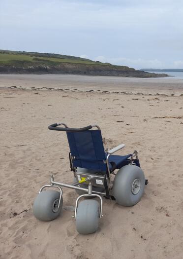 A beach wheelchair on the sandy foreshore of West Angle Bay in Pembrokeshire Coast National Park.