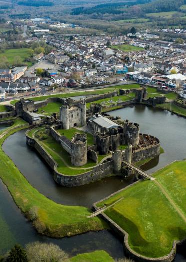 Aerial shot of Caerphilly Castle surrounded by the moat and green banks.