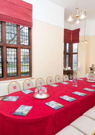 A board room style meeting room with red and cream decor and catering facilities.