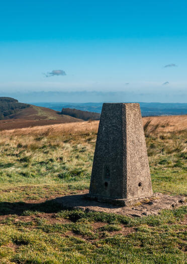 A stone plinth at the top of a mountain with far reaching views.