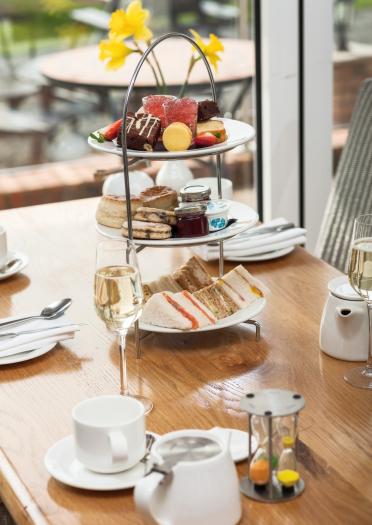 Sandwiches and cakes on a three tiered plate with afternoon tea.