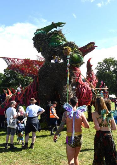 Giant green man and red dragon sculptures amongst party revellers at Green Man Festival.
