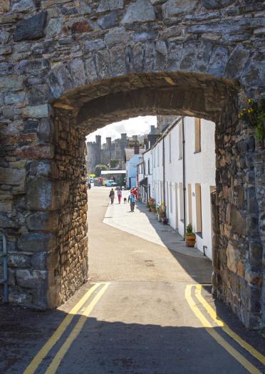 A view of Conwy castle and pretty houses of Conwy through an arch in the town wall.