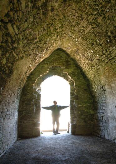 Silhouette of a man looking inside and ancient stone walled dungeon