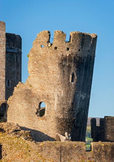 Der schiefe Turm einer Burg, der von einer hölzernen Statue innerhalb der Burgmauern gestützt wird.