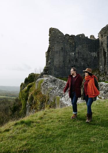 Ein Paar, das im Herbst in der Nähe der Ruinen einer Burg spazieren geht.