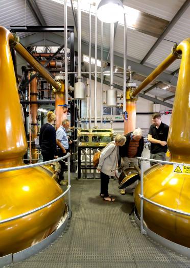Eine Gruppe besichtigt das Innere der Penderyn Whisky-Brennerei.