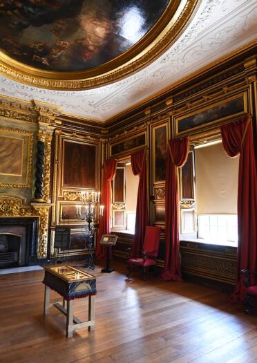 A grand room with an ornate fireplace and domed painted ceiling.