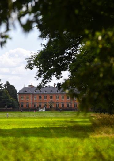 An external view of the grand Tredegar House surrounded by trees and lawns.