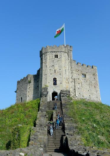 People walking up steps leading up to a castle keep on a hill.