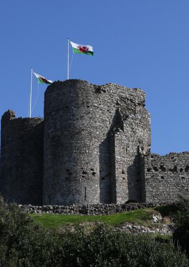Criccieth Castle on a hill with two Welsh flags waving