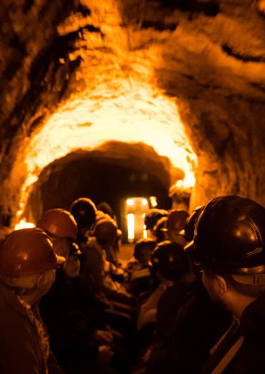 Eine Gruppen Personen mit Helmen in einem erleuchteten Tunnel.