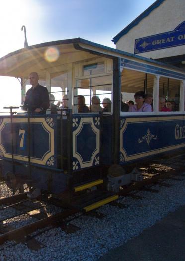 Passengers on Great Orme Tramway, Llandudno as it passes the coast in the background.