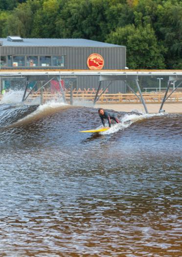 Two people taking off on a wave at Surf Snowdonia, in North Wales