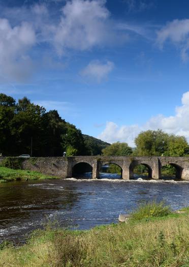 Man fishing in front of bridge over the River Usk, Abergavenny.