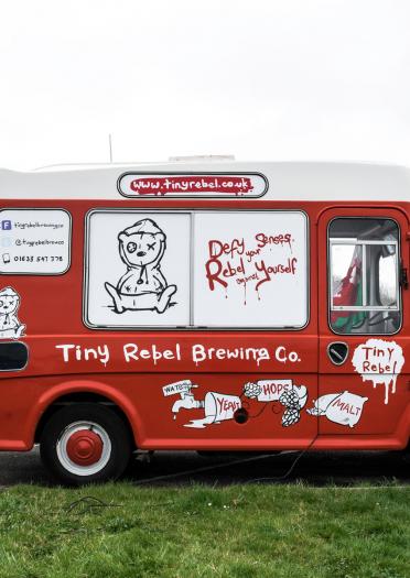 Side view of branded red and white Tiny Rebel Brewing Co van.