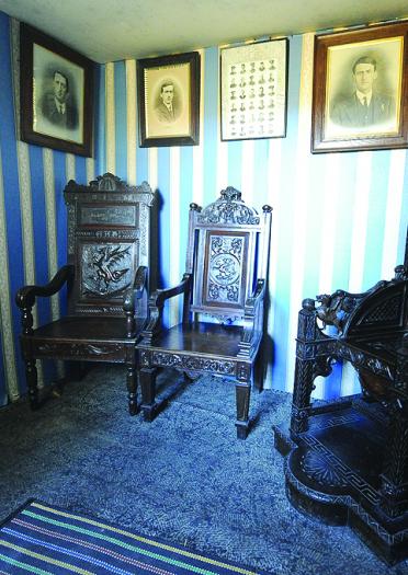 Image of a room with three large bardic chairs and family pictures on the wall.