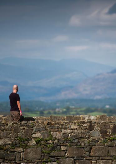 Ein Mann bewundert die Aussicht auf die Berge von Harlech Castle aus. 