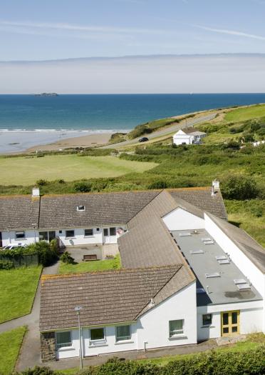 YHA Broad Haven building with the beach and sea in the distance.