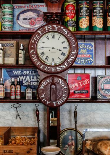 Old fashioned shop displaying groceries on shelves by a clock at St Fagans National Museum of History.