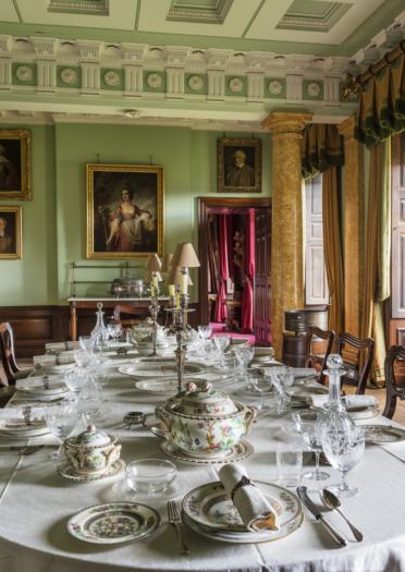 A table set for grand dining with portraits on the wall and a pillar in the background at Erddig House.