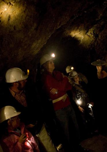 dark gold mine with visitors with hard hats with lights